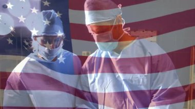 Maskeli cerrahların üzerinde sallanan Amerikan bayrağının animasyonu. küresel covid 19 salgın hastalık ve sağlık hizmetleri konsepti dijital olarak oluşturulmuş video.