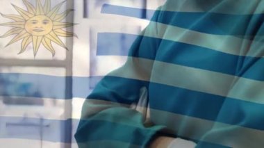 Yüz maskeli cerrahların üzerinde sallanan uruguay bayrağının animasyonu. küresel covid 19 salgın hastalık ve sağlık hizmetleri konsepti dijital olarak oluşturulmuş video.