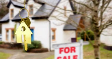 Altın evin anahtarlığının animasyonu, satılık tabelası olan bulanık evin önünde asılı duruyor. gayrımenkul işi, ev ve finans kavramı dijital olarak üretilen video.