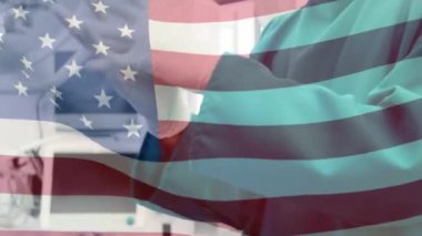 Maskeli cerrahların üzerinde sallanan Amerikan bayrağının animasyonu. küresel covid 19 salgın hastalık ve sağlık hizmetleri konsepti dijital olarak oluşturulmuş video.