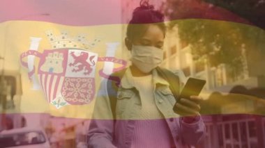 Yüz maskeli bir kadının üzerinde sallanan spainl bayrağının animasyonu. küresel covid 19 salgın hastalık ve sağlık hizmetleri konsepti dijital olarak oluşturulmuş video.
