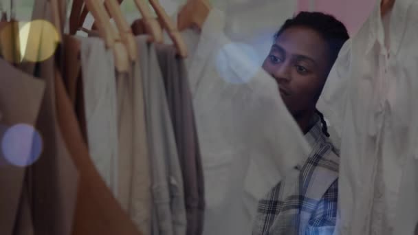 Animación Luces Bokeh Sobre Hombre Afroamericano Ordenando Exhibición Ropa Tienda — Vídeos de Stock