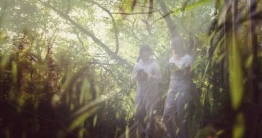 İki mutlu Asyalı kadının çay ve yürüyen ormanları, hareket eden çimenleri ve doğayı birleştirmesi. sağlık, zindelik ve refah konsepti dijital olarak oluşturulmuş video.