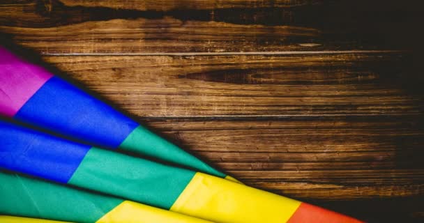 木製のテーブルの背景にLqbtqテキストと虹の旗のアニメーション Lgbtq誇りと平等のお祝いの概念デジタル生成されたビデオ — ストック動画