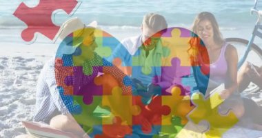 Renkli yapboz parçalarının animasyonu plajdaki mutlu insanlara karşı yürek ister. - Evet. otizm, öğrenme güçlüğü, destek ve farkındalık kavramı dijital olarak oluşturulmuş video.