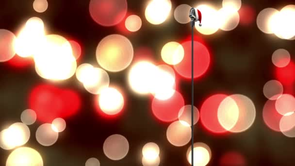 黒を背景に赤と黄色の光のスポットに対してマイクの上にサンタの帽子 クリスマス音楽とお祝いのコンセプト — ストック動画