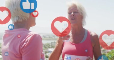 Sosyal medya simgelerinin canlandırılması, mutlu yaşlı kadınların su içmesi ve kumsalda gülüşmeleri..
