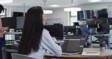 Masada oturan Asyalı kadın dizüstü bilgisayardan veri işleme programını izliyor. bilgisayar kodlaması, veri teknolojisi ve dijital arayüz konsepti dijital olarak oluşturulmuş video.