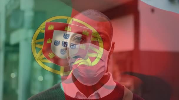 流行19の流行の間に顔のマスクを身に着けている男の上に手を振るポルトガルの旗のアニメーション 世界中で流行している19の概念をデジタルで — ストック動画
