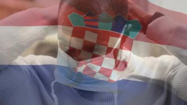 Covid 19 salgını sırasında yüzü maskeli bir adamın üzerinde sallanan Hırvat bayrağının canlandırılması. küresel covid 19 salgın konsepti dijital olarak oluşturulmuş video.