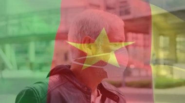 Covid 19 salgını sırasında yüz maskesi takan adamın üzerinde sallanan kamerun bayrağı animasyonu. küresel covid 19 salgın konsepti dijital olarak oluşturulmuş video.
