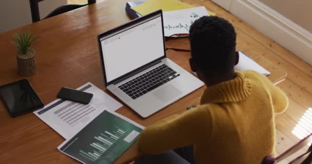 アフリカ系アメリカ人の男性は ノートパソコンの画面でコーディングデータ処理を見て机に座っています コンピュータ コーディング データ技術 デジタル インターフェースの概念がデジタルで生成されたビデオ — ストック動画