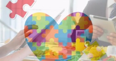 Dijital cihazlar kullanarak iş adamlarının üzerine renkli yapboz parçaları ve otizm metinlerinin animasyonu. otizm, öğrenme güçlüğü, destek ve farkındalık kavramı dijital olarak oluşturulmuş video.