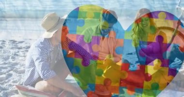 Renkli yapboz parçalarının animasyonu plajdaki mutlu insanlara karşı yürek ister. - Evet. otizm, öğrenme güçlüğü, destek ve farkındalık kavramı dijital olarak oluşturulmuş video.