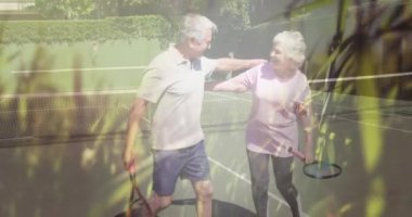 Tenisten sonra çimen ve doğa ile kucaklaşan mutlu Kafkasyalı son sınıf çifti. Sağlıklı emeklilik, zindelik ve refah konsepti dijital olarak oluşturulmuş video.