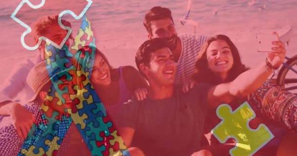 夏のビーチパーティーでセルフィーを撮る幸せな友人の上にカラフルなパズルピースリボンのアニメーション 自閉症学習困難支援意識概念デジタルで生成されたビデオ — ストック動画