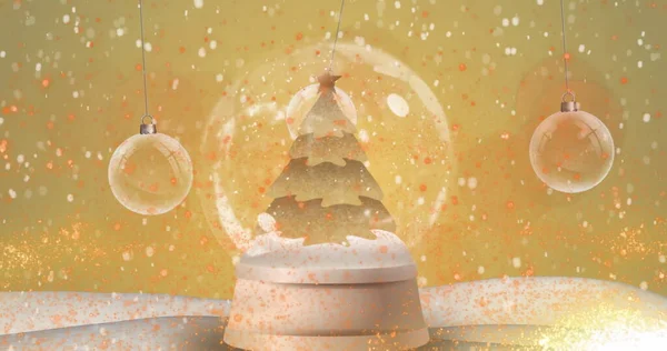 雪の地球でクリスマスツリーの周りに回転流れる流れ星の上に落ちる雪のデジタル画像と黄色の背景に対する手の装飾 — ストック写真