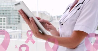 Tablet kullanarak gülümseyen kadın doktorun üzerinde yüzen pembe kurdele kanser logolarının animasyonu. Göğüs kanseri pozitif kadın sağlığı bilinçlendirme kampanyası konsepti dijital olarak üretilen video.