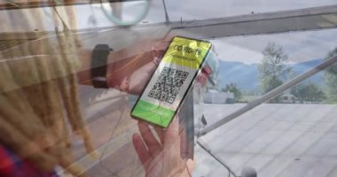 Adamın elinde QR kodlu bir akıllı telefonu havaalanındaki özel plana karşı tutmasının bileşimi. covid-19 aşı sertifikası ve sağlık kartı konsepti