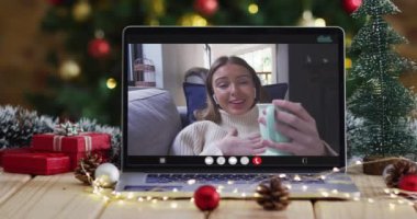 Dizüstü bilgisayarında, Noel süslemeleri ve ağacı olan mutlu beyaz kadın. Noel, şenlik ve iletişim teknolojisi dijital kompozit video.