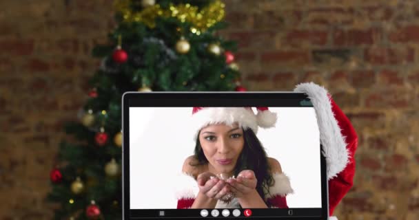 身穿圣塔服装的白人妇女在电脑上通过视频通话 带着圣诞装饰品和圣诞树 节日和通信技术数码合成录像 — 图库视频影像