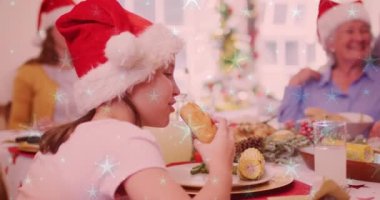 Gülen beyaz bir ailenin üzerine düşen kar animasyonu. Noel Baba şapkalarıyla yemek yiyorlar. Noel, kış, gelenek ve kutlama konsepti dijital olarak oluşturulmuş video.