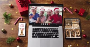 Aile bilgisayarında video başında şapka takıyor, akıllı telefon, tablet ve dekorasyonları var. Noel, şenlik ve iletişim teknolojisi dijital kompozit video.