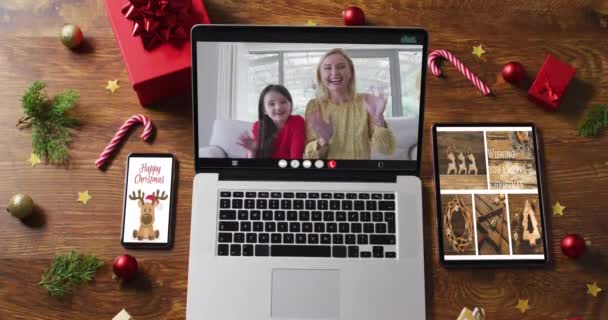 带着智能手机 平板电脑和圣诞装饰品的妈妈和女儿在笔记本电脑上通过视频通话 节日和通信技术数码合成录像 — 图库视频影像