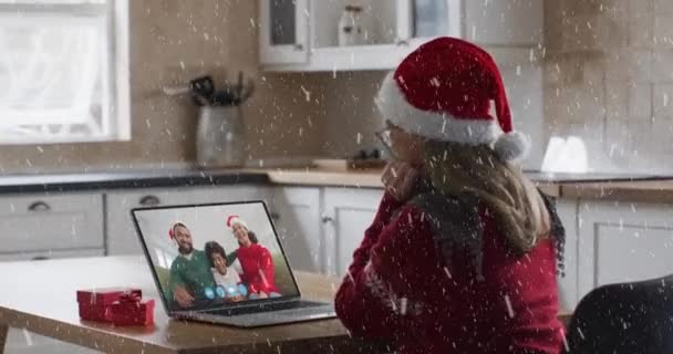 ラップトップのビデオ通話でサンタの帽子の幸せな白人女性に落ちる雪のアニメーション クリスマス お祝いのコンセプトをデジタルで — ストック動画