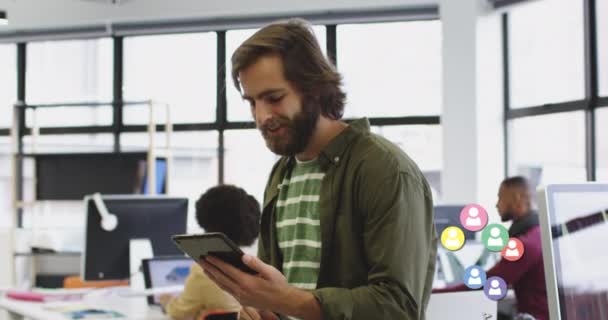 Animación de los iconos de los medios de comunicación sobre sonriente hombre de negocios caucásico usando tableta — Vídeos de Stock