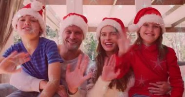 Gülümseyen beyaz bir ailenin üzerine yağan kar animasyonu. Noel Baba şapkalarıyla el sallıyor. Noel, kış, gelenek ve kutlama konsepti dijital olarak oluşturulmuş video.