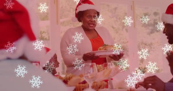 戴着圣诞礼帽的笑容满面的一家人正在吃晚餐 雪地的动画笼罩着他们 圣诞节 传统和庆祝概念数字制作的视频 — 图库视频影像