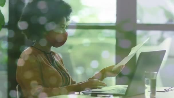 Animation of media icons over diverse business people wearing face masks and holding document — Stock Video
