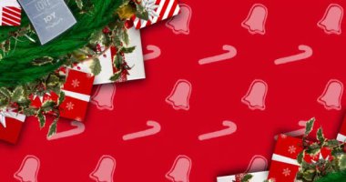 Kırmızı arka planda Noel süsleri, çanlar ve şeker kamışları desenleri. Noel, kış, gelenek ve kutlama konsepti dijital olarak oluşturulmuş video.