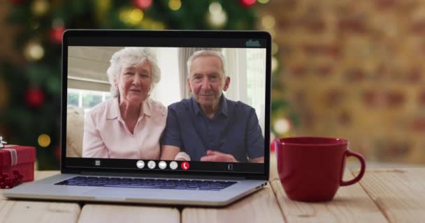 白种人的老夫妇在笔记本电脑上边看边挥手 带着圣诞树 节日和通信技术数码合成录像 — 图库视频影像
