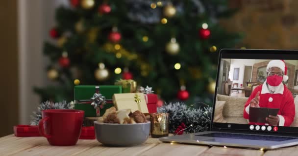 Afro Amerikaanse Santa Gezicht Masker Video Oproep Laptop Met Kerstversiering — Stockvideo