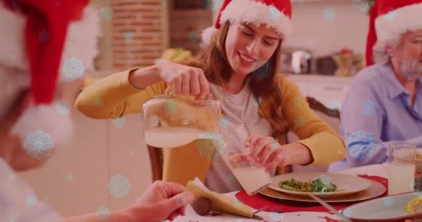 白雪飘扬在笑容满面的高加索家庭头上 戴着圣诞礼帽在吃饭 圣诞节 传统和庆祝概念数字制作的视频 — 图库视频影像