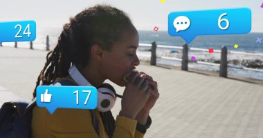 Deniz kenarında sandviç yiyen bir kadın, sırt çantalı kulaklıklar ve sosyal ikonlar, fotokopi alanı. Kıyı, eğlence, rahatlama, yaşam tarzı, canlı, modern, iletişim