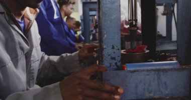 Fabrikada mavi hidrolik pres kullanan gri tulumlu sürükleyici operatör, kopyalama alanı. Endüstriyel, imalat, takım çalışması, hassasiyet, makine, üretkenlik, endüstriyel tasarım