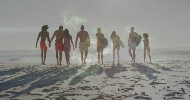 Mayolu sekiz sörfçüden oluşan yürüyen bir grup, kumsalda okyanusa doğru sörf tahtaları taşıyor. Sahil, eğlence, açık hava, macera, yaşam tarzı, canlılık, doğa.