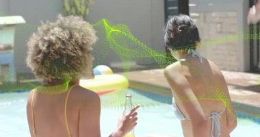 Havuz başında elinde şişe tutan iki kadın, erkek gibi zıplıyor ve yaşam tarzı reklamları için canlı su sıçratıyor. Yaz zamanı, boş zaman, açık hava, arkadaşlık, rahatlama, canlı, neşeli