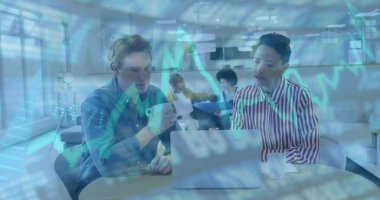Viewing laptop and holding coffee mug, blue-shirted man analyzing financial data in office lounge. Collaboration, teamwork, modernoffice, innovation, dataanalysis, businessmeeting, professional