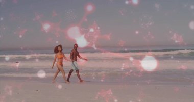 Bikinili ve yüzme şortlu çiftler pembe yıldız kaplamalı sahil şeridi boyunca ilerliyorlar. Romantik, boş zaman, deniz kenarı, tatil, siluet, manzara, ufuk