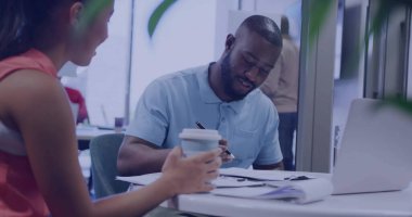 Mavi polo tişört giyen yetişkin bir siyahi adam, ofiste gümüş dizüstü bilgisayarla dokümanları tamamlıyor. İşbirliği, takım çalışması, profesyonel, işyeri, modern, tarafsız, üretkenlik