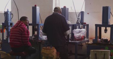 Fabrika teknisyenleri atölyede hidrolik pres makineleri çalıştırıyor, paketlenmiş kırmızı parçaları ayırıyorlar. Sanayi, işçilik, makine, üretim, hassasiyet, takım çalışması, üretkenlik