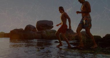 Gün batımında sığ sularda dengeli yürüyen gömleksiz adamlar renkli şortlarıyla sahilde yürüyorlar. Macera, dostluk, sahil, eğlence, coşku, keşif, açık hava