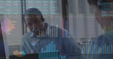 Profesyonel gömlekli ve kulaklıklı, masadaki mali verileri analiz eden, dizüstü bilgisayarlı ve çizelgeli. İş, finans, teknoloji, işbirliği, analitik, iş istasyonu, profesyonel