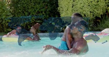 Baba yüzen damlacıklarla sıhhatli bir bağ kurmak için havuz suyunu yudumluyor ve oğluna su sıçratıyor. Aile, eğlence, eğlence, yaz, kaynaşma, açık hava, neşe