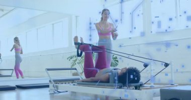 Eğitmen, Pilateste yayların baskısına rehberlik eden akıllı hareket hareketli ritim çubuğunu tıklatıyor. Spor, sağlık, rehabilitasyon, güç, hareket, farkındalık, modern