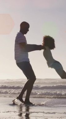 Mutlu Afro-Amerikan babası ve kızı güneşli sahilde olan beneklerin animasyonu. Dijital ortamda üretilen sağlıklı ve aktif plaj tatili konsepti.